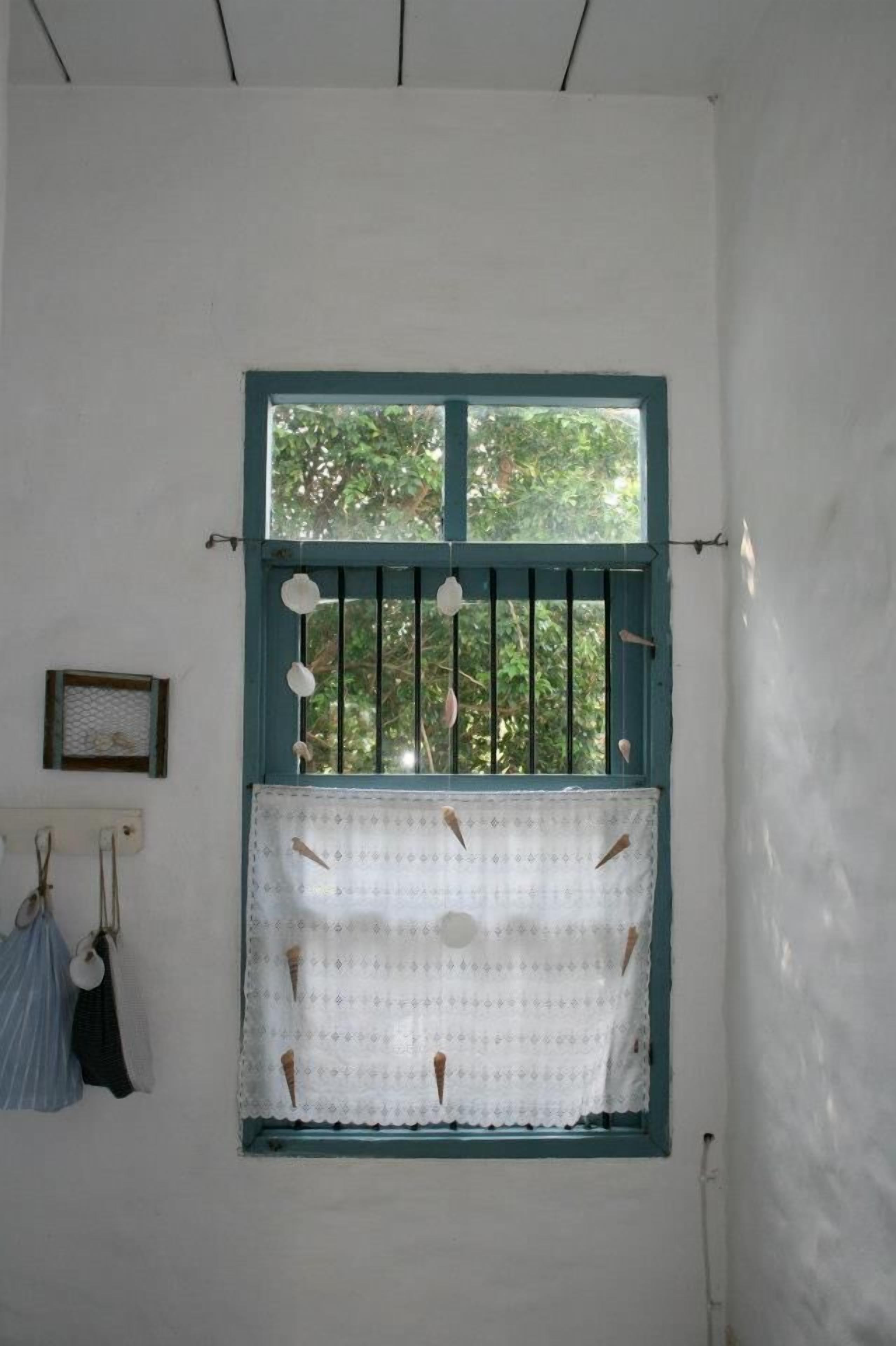 A room with a window featuring a blue frame and a white lace curtain.