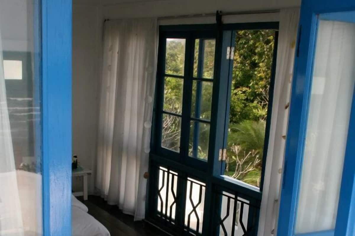 A room with a bed, a small table, and a window with curtains.