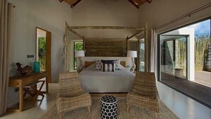 Un dormitorio con una cama grande, dos sillas, una mesita redonda y vistas al bambú.