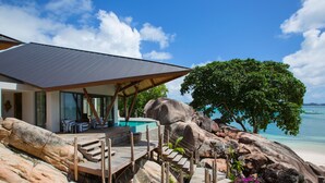 Un moderno resort con piscina, terraza de madera y vista al océano.