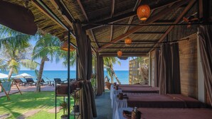 Una habitación frente a la playa con camas, vista al océano y palmeras.