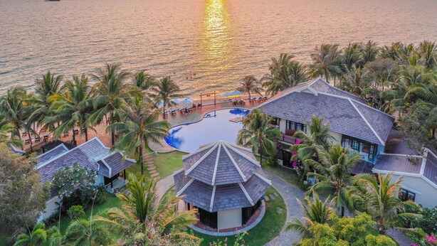 Un resort con piscina, palmeras y vistas al atardecer.