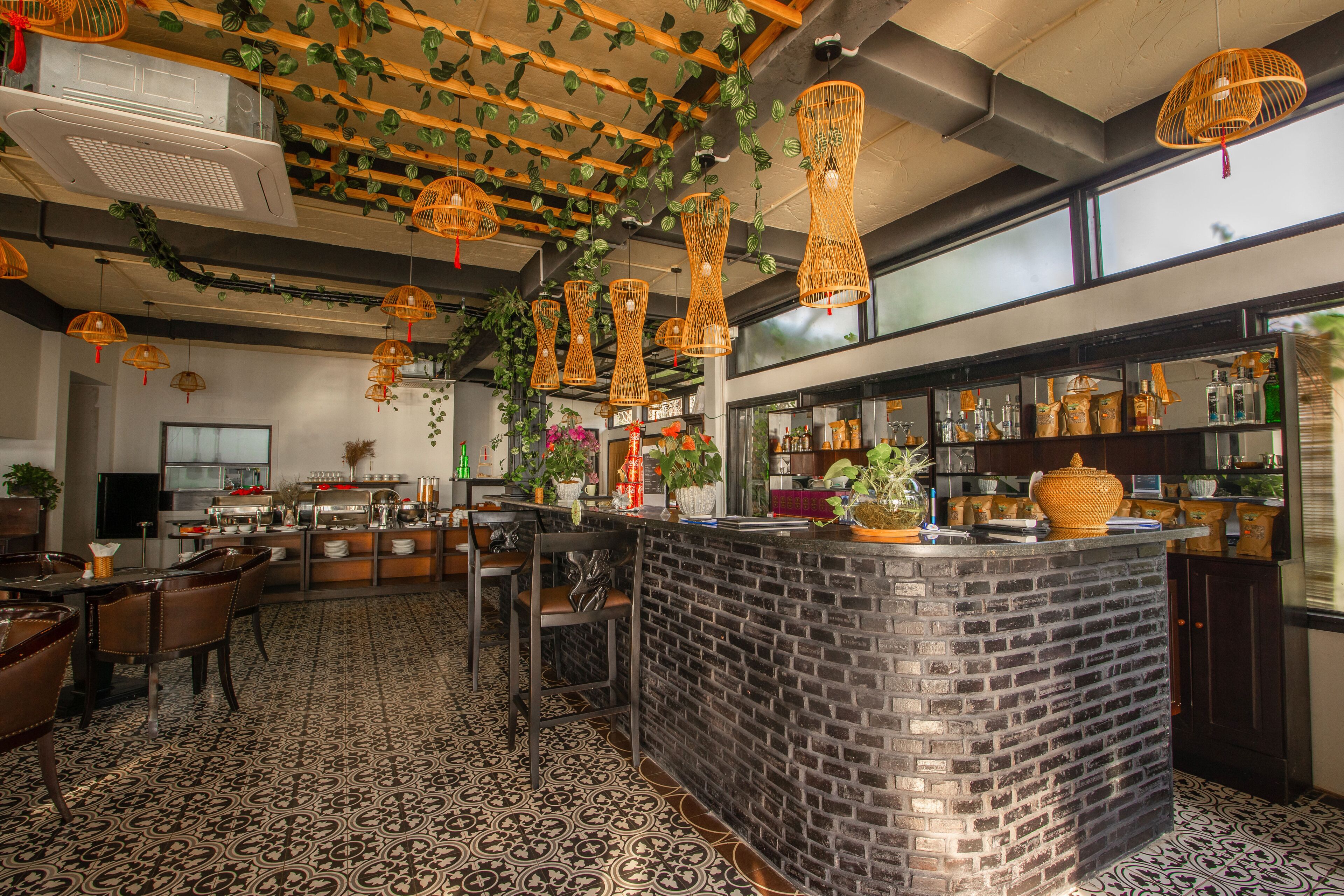 A restaurant with a brick counter, hanging wicker lights, and patterned flooring.