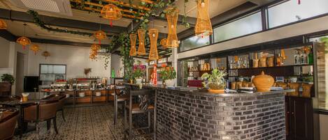 A restaurant with a brick counter, hanging wicker lights, and patterned flooring.