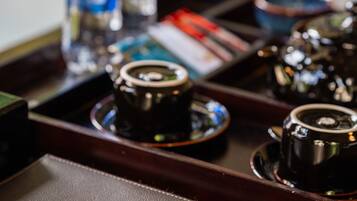 A close-up of a leather-bound book with the name "Ania" embossed on the cover, placed on a tray with various items including a coffee cup and bottles.