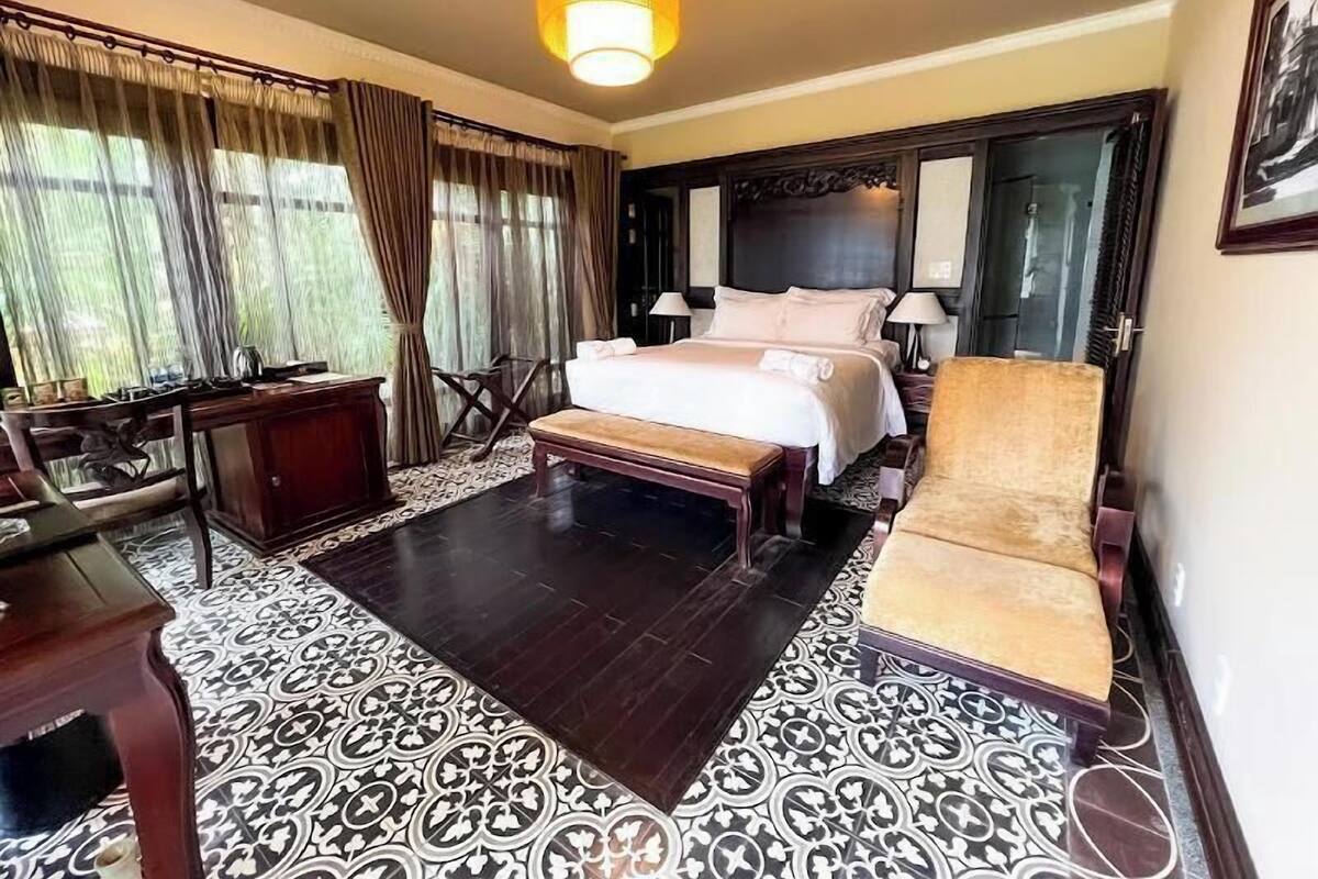 Una camera d'albergo con un letto, comodini, una scrivania, una sedia e pavimento decorato.