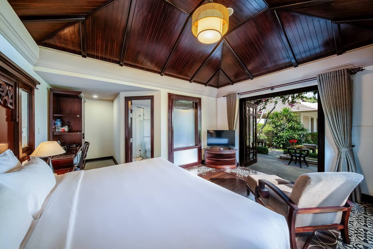 Una camera d'albergo con un letto grande, una televisione, una scrivania e vista sul giardino esterno.