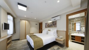 A modern hotel room with a large bed, a bedside table with a lamp, a built-in TV, a wardrobe, and a bathroom with a large mirror and sink. - Nishant Boutique Hotels (Istanbul)