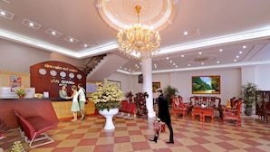 A hotel lobby with a check-in counter, a chandelier, and traditional red chairs. - Van Giang Hotel (Ninh Binh)