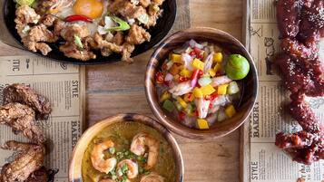 A variety of dishes including fried chicken, shrimp, and stir-fried vegetables, arranged on a wooden table with newspaper-style placemats.