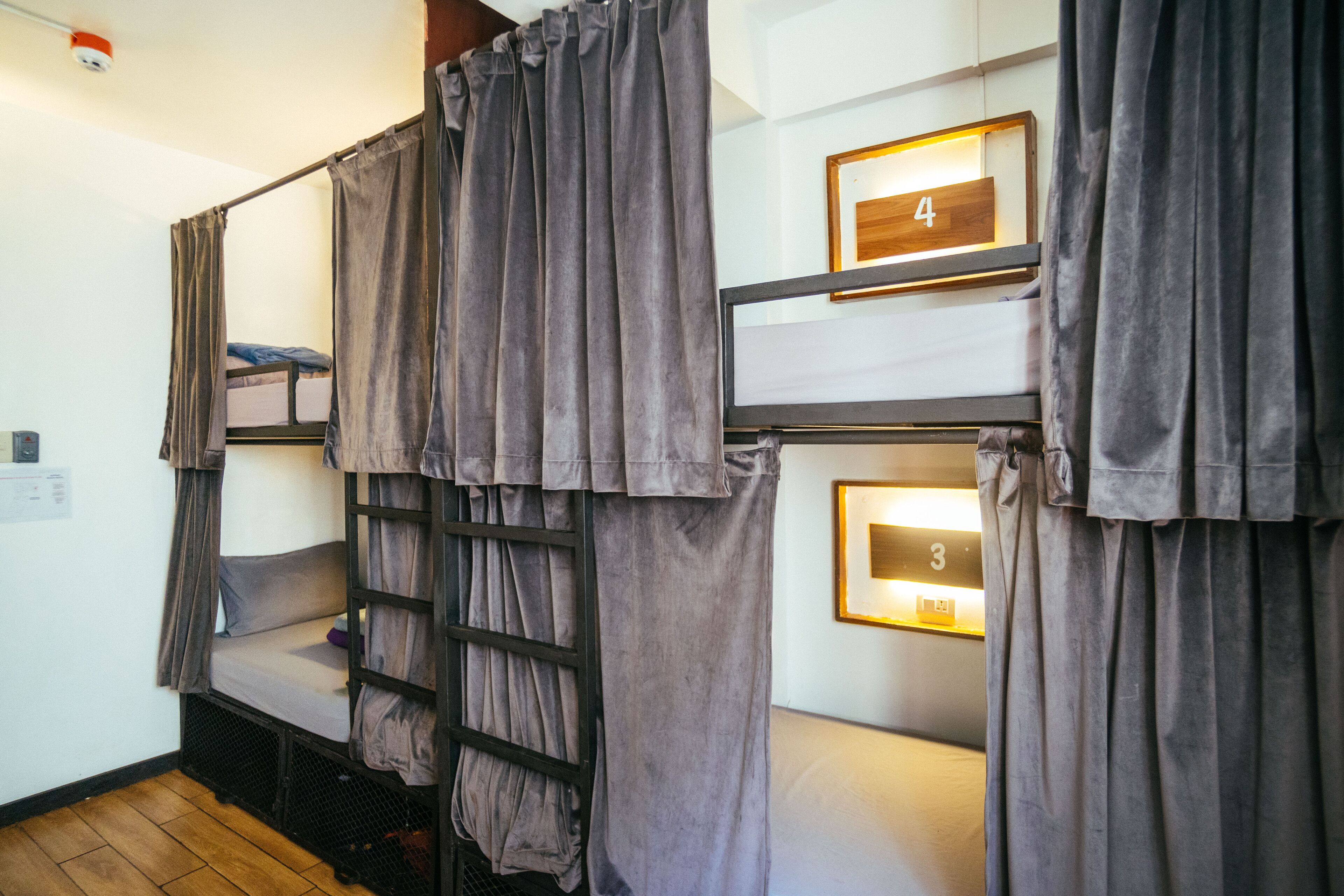 Un dormitorio con literas, cortinas y carteles con números de habitación.