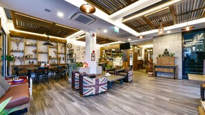 A spacious lobby with wooden flooring, a coffee shop area, and a statue on display. - Casa Bella Phuket (Chalong)