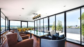 A modern lounge with a glass table, comfortable seating, and a view of the cityscape. - Casa Bella Phuket (Chalong)