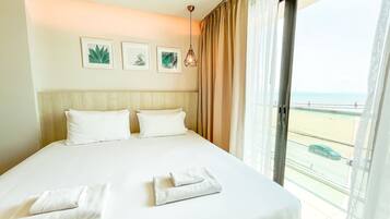 A hotel room with a large bed, beige curtains, and a view of the beach.