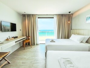 A hotel room with a bed, a desk, a chair, a TV, and a view of the ocean. - Zand Morada Pattaya (Pattaya)