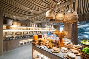 A buffet area with various food items and utensils, a woven ceiling, and a display of baskets and pottery. - Zand Morada Pattaya (Pattaya)