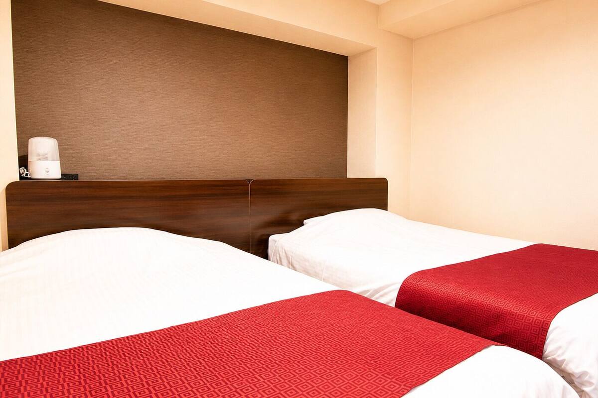 A hotel room with two beds, a wooden headboard, and a wall-mounted coffee maker.