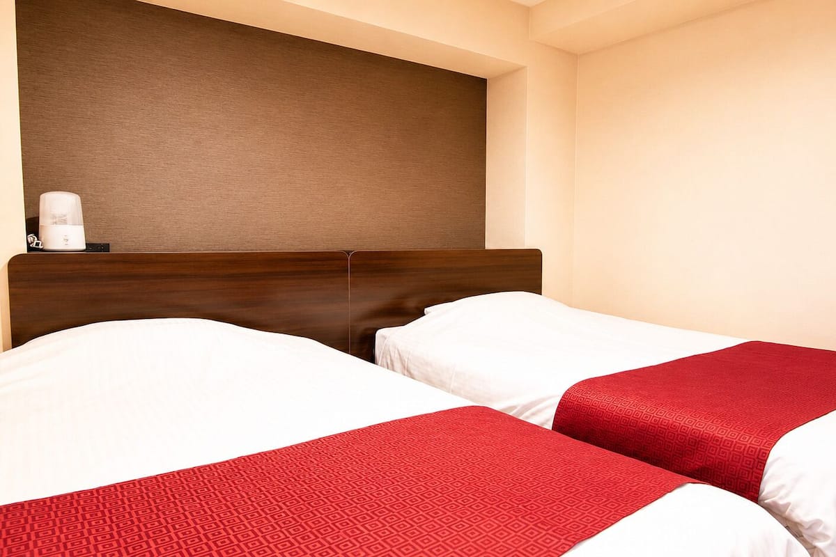 Una habitación de hotel con dos camas, un cabecero de madera y una cafetera de pared.