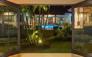 Et moderne hus med swimmingpool, omgivet af frodig vegetation og palmer.
