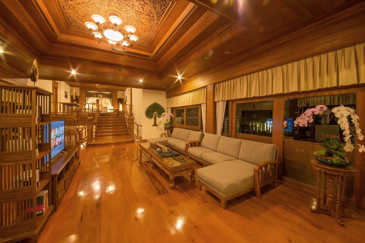 Un amplio salón con escalera de madera, un conjunto de sofás, una mesa de centro y un televisor.
