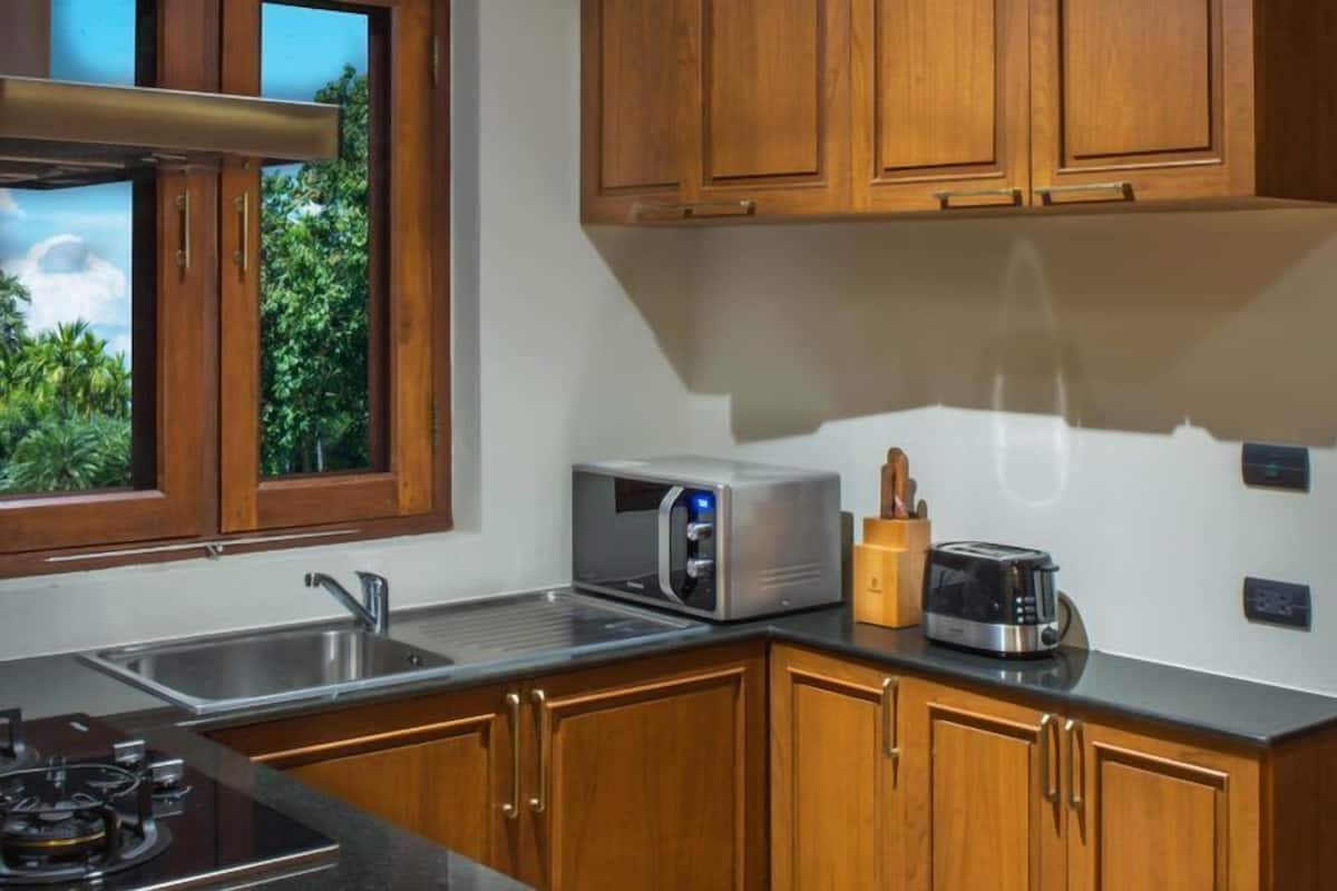 Una cocina moderna con armarios de madera, microondas integrado, tostadora y estufa a gas.