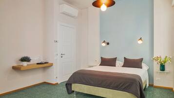A bedroom with a bed, a bedside table, a hanging light fixture, and a wall-mounted air conditioner.
