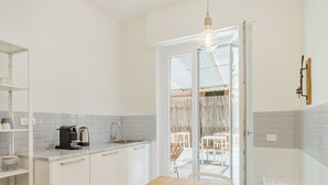 Una cocina con armarios blancos, una mesa de madera y una cafetera.