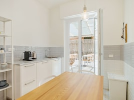Una cocina con armarios blancos, una mesa de madera y una cafetera.