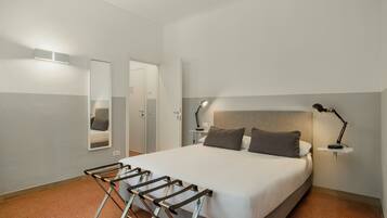 Un dormitorio con una cama, dos lámparas de noche, un espejo y una puerta.