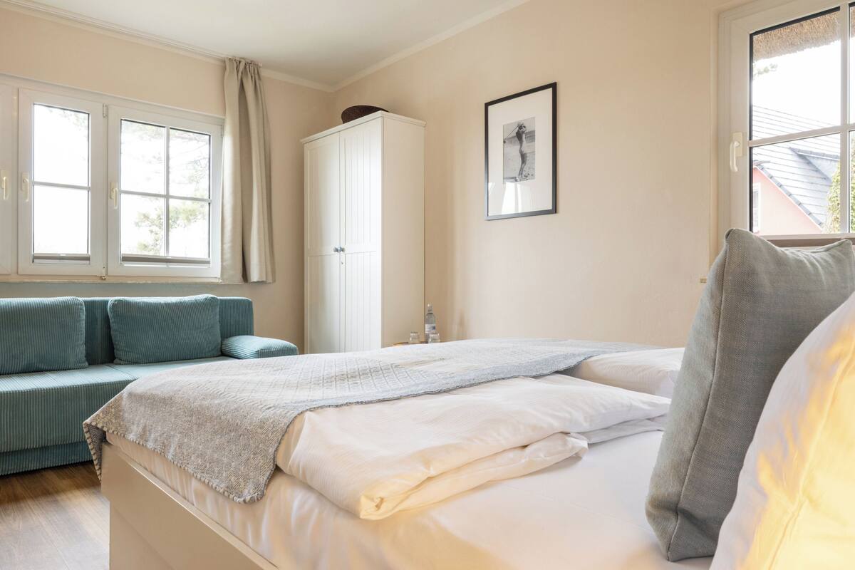 A bedroom with a bed, a sofa, a wardrobe, and a window.