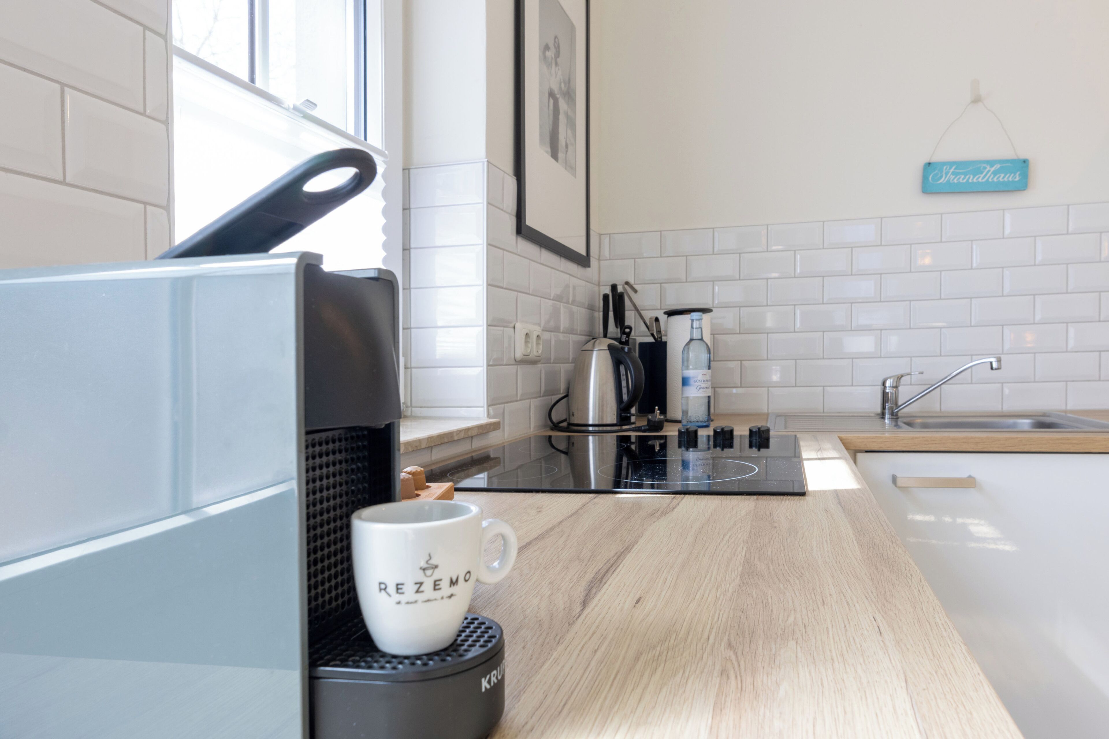 Una cucina moderna con una macchina da caffè, una tazza e un cartello con la scritta 'Shandhaus'.