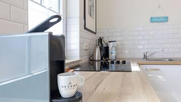 A modern kitchen with a coffee machine, a mug, and a sign that reads 'Shandhaus'.