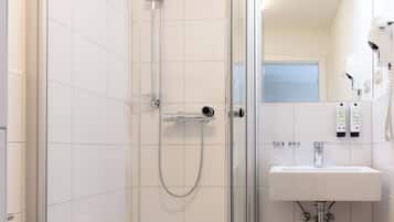 Ein modernes Badezimmer mit einer gläsernen Dusche, einem weißen Waschbecken und einem Holzboden.