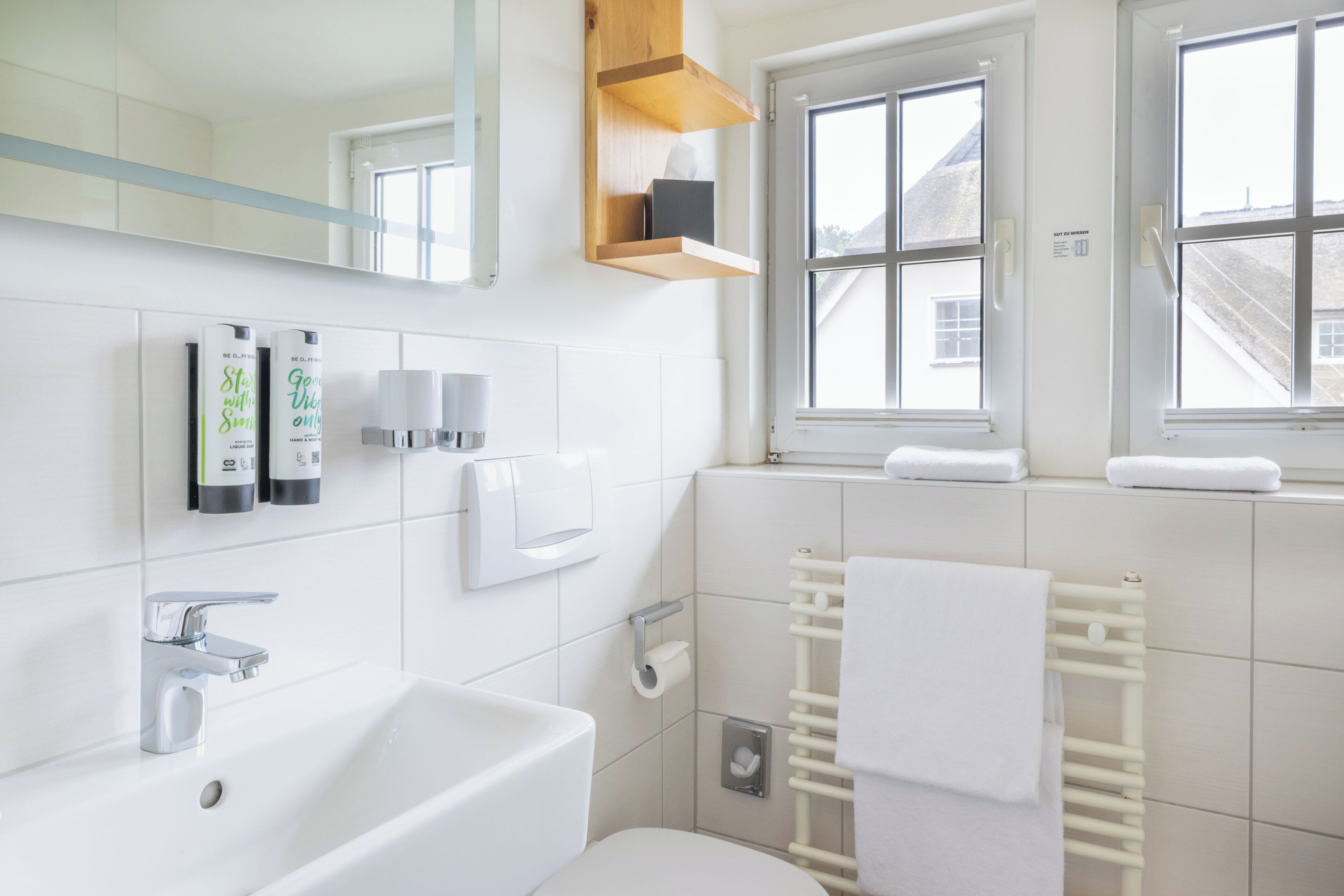 Een moderne badkamer met een wit wastafel, spiegel en handdoekhouder.