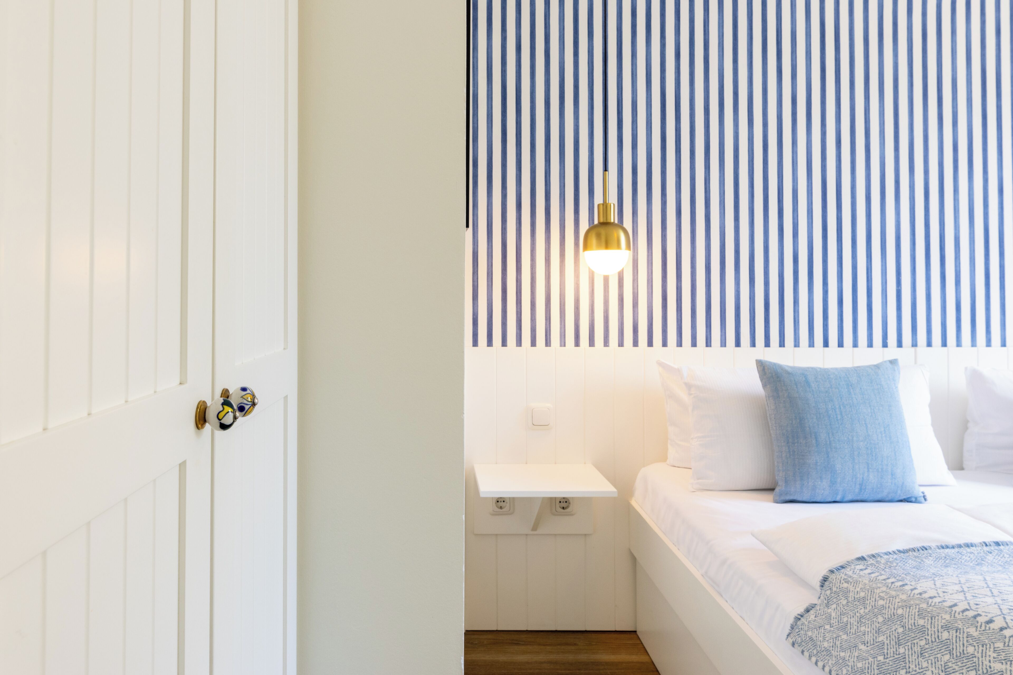Ein Schlafzimmer mit Bett, Nachttisch und Pendelleuchte.