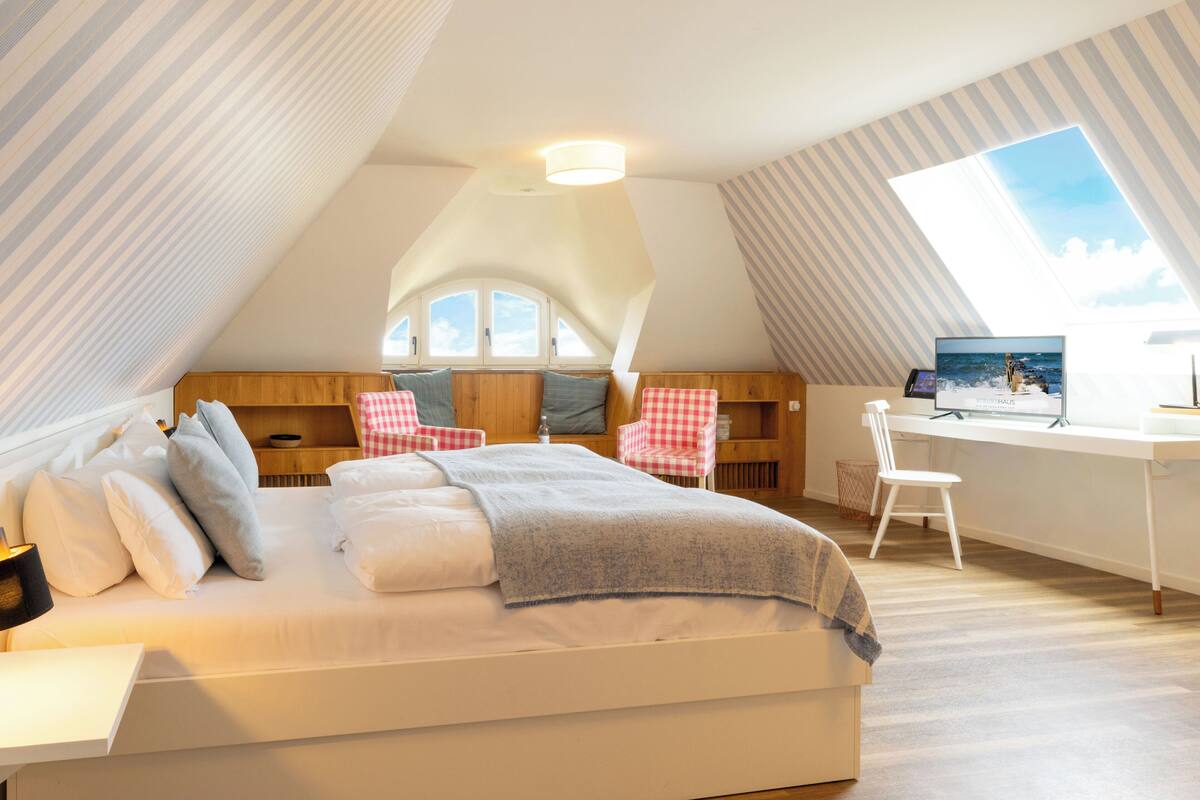 A bedroom with a bed, a desk, a chair, and a window.