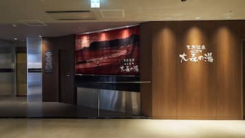 A modern hotel lobby with a large wall mural, a reception desk, and wooden paneling.