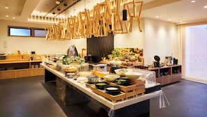 Un restaurante moderno con una zona de buffet central, mobiliario de madera y lámparas colgantes.