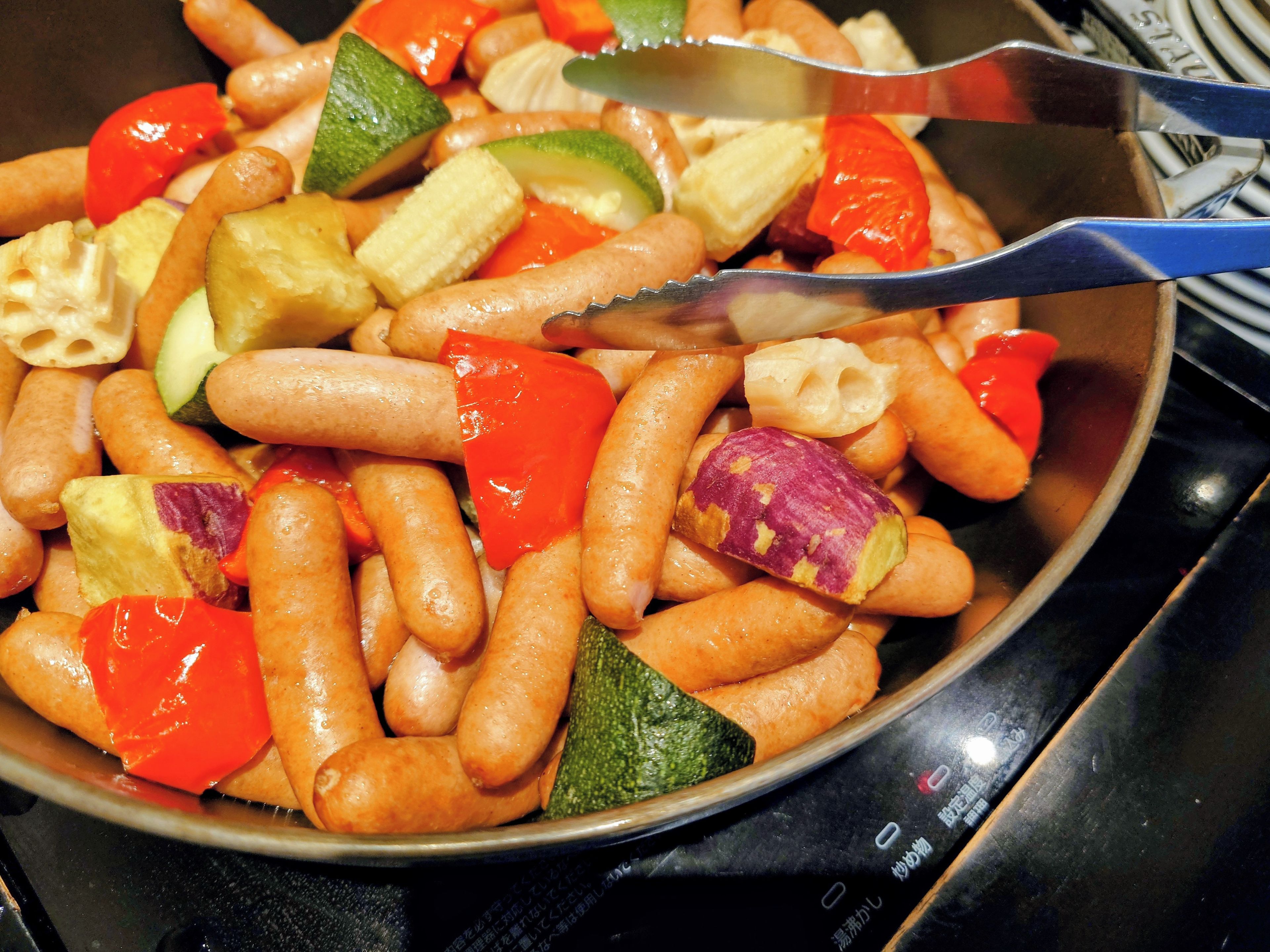 Une poêle remplie de divers légumes et de saucisses.