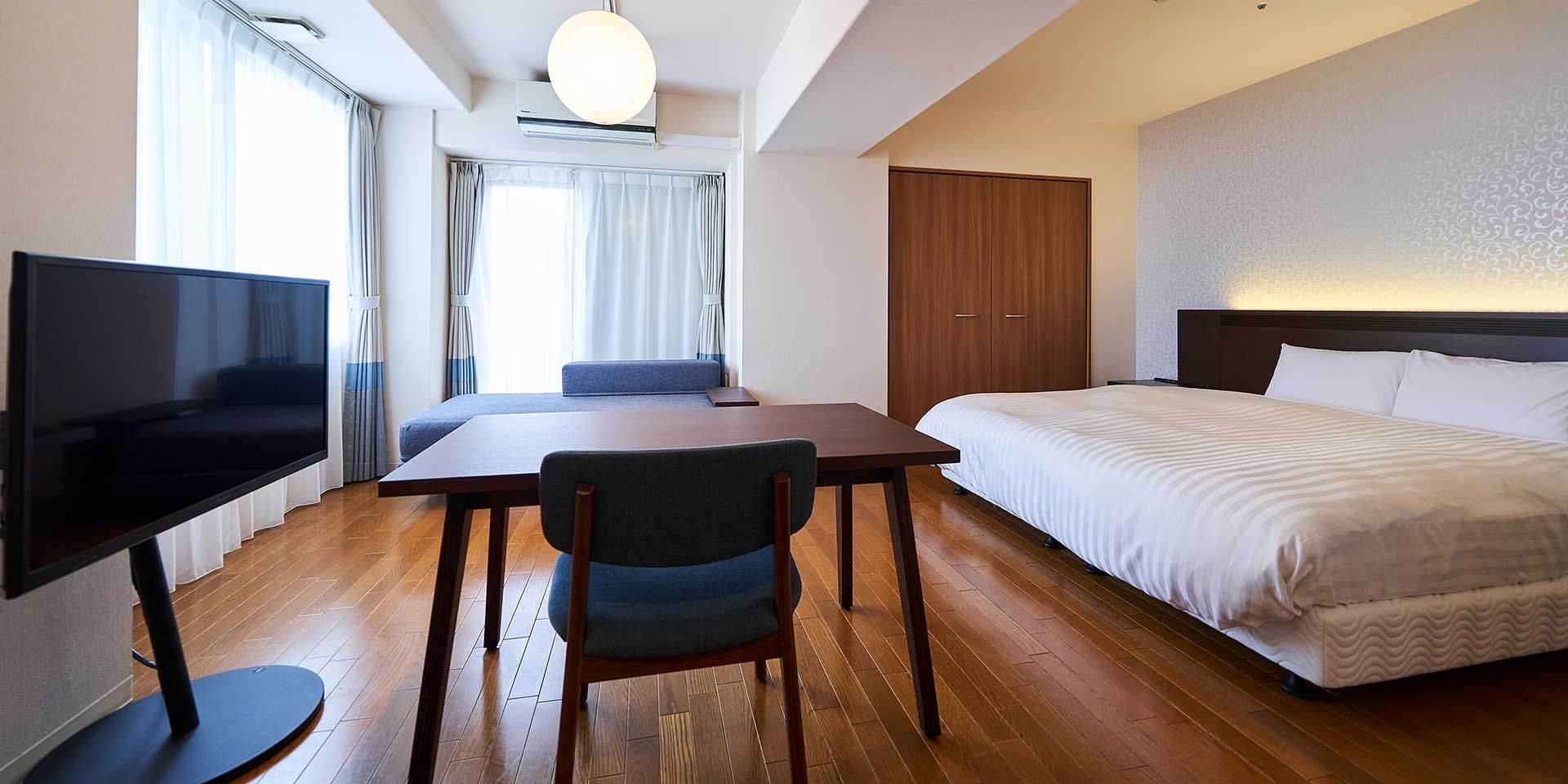 A hotel room with a bed, a TV, a desk, and a chair.