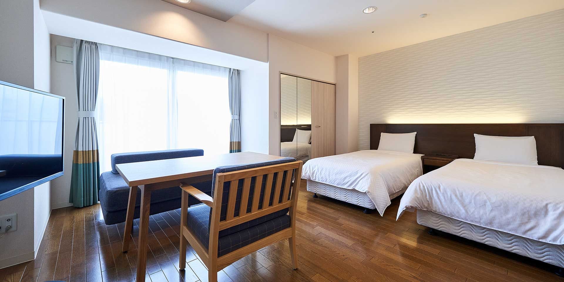 A hotel room with a bed, a desk, a chair, and a television.