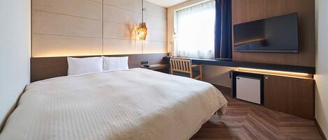 A hotel room with a bed, bedside table, lamp, TV, and a small cabinet.