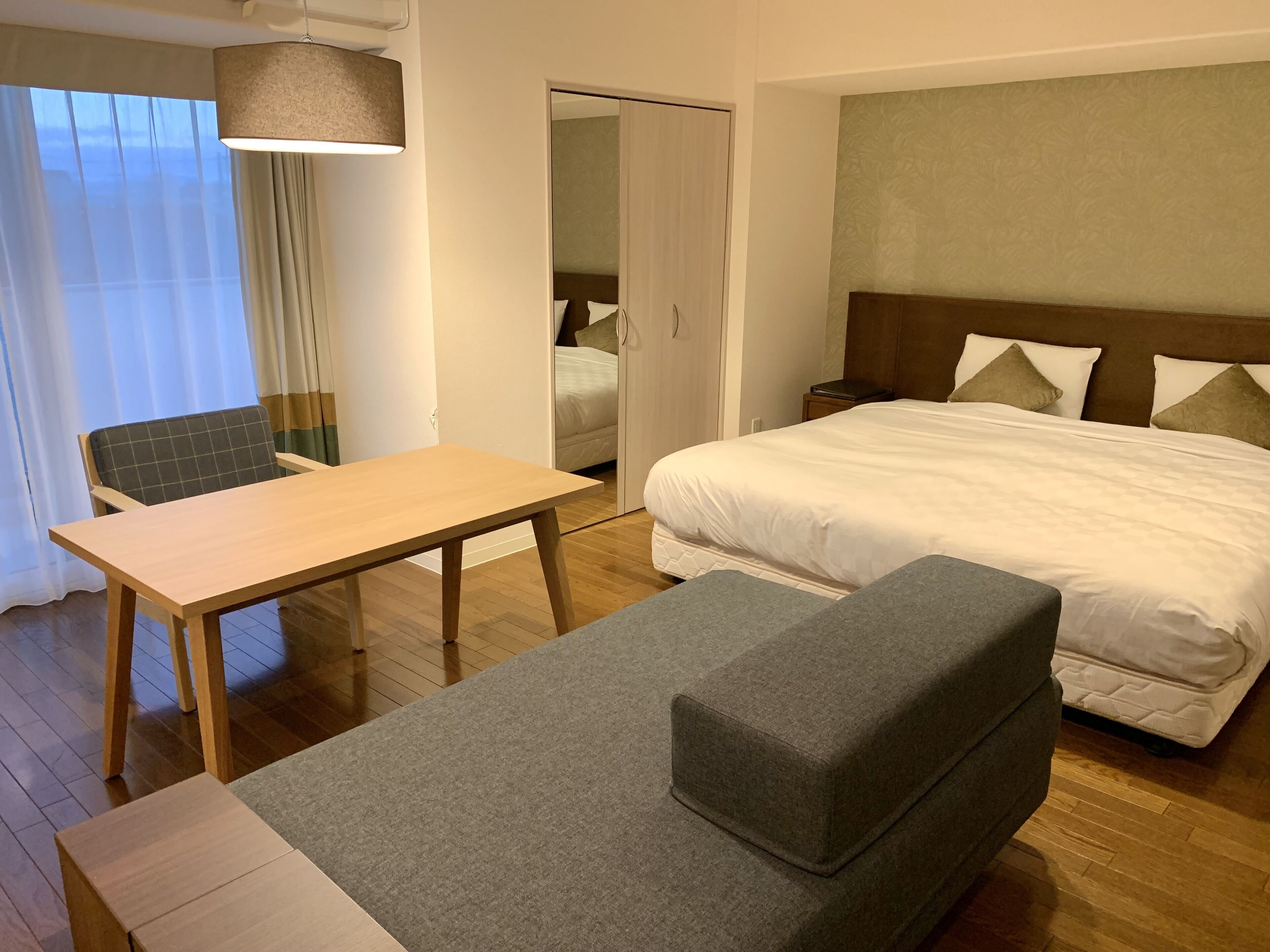 A hotel room with a bed, a table, a chair, and a sofa.