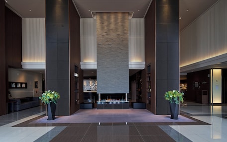 A spacious lobby with a central seating area, large pillars, and potted plants.