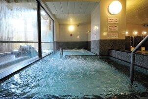 Un bain dans une source thermale, avec vue sur l’extérieur grâce à une grande fenêtre.