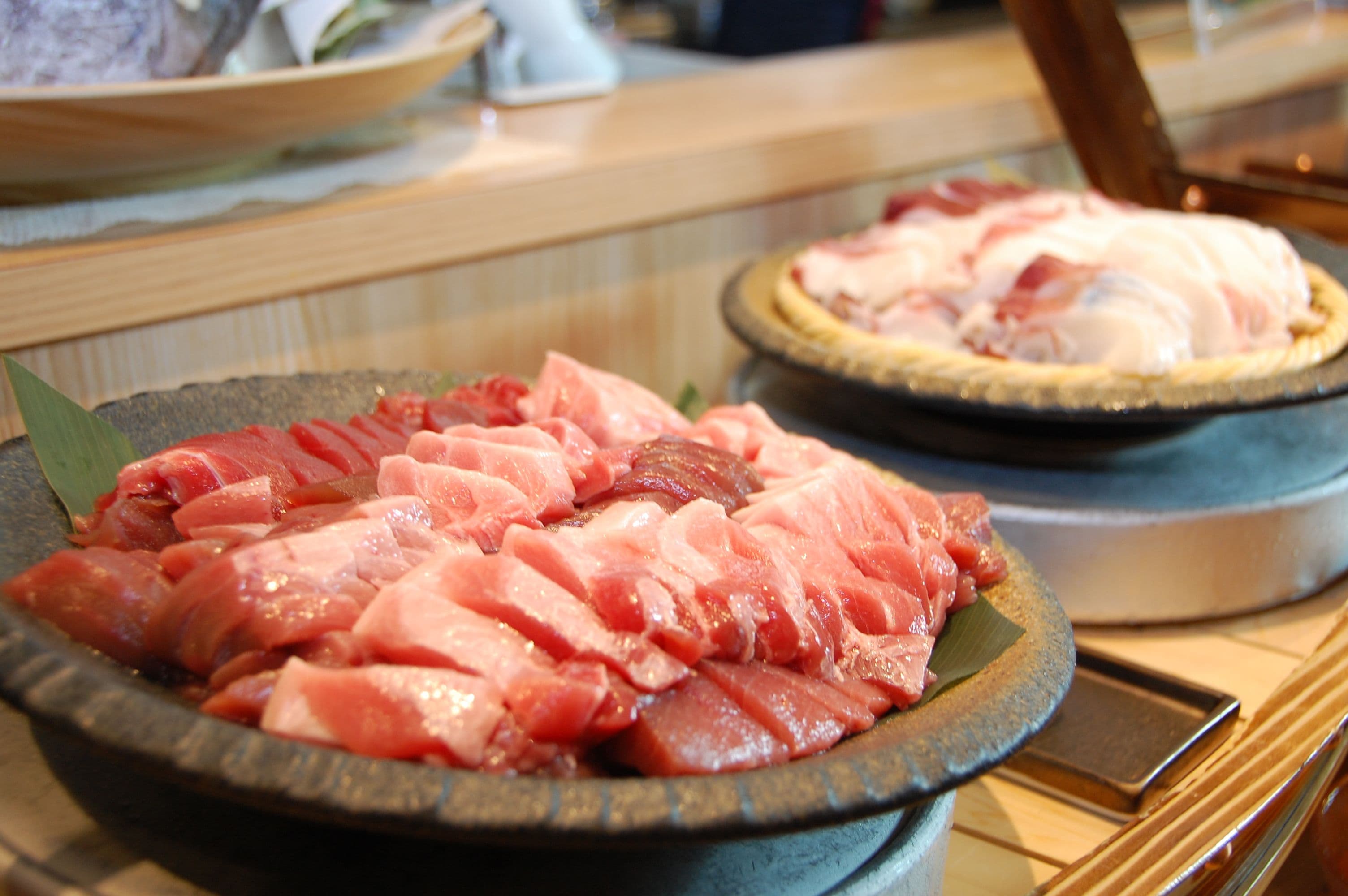 Un bar de sushi con una variedad de pescado fresco exhibido en bandejas.