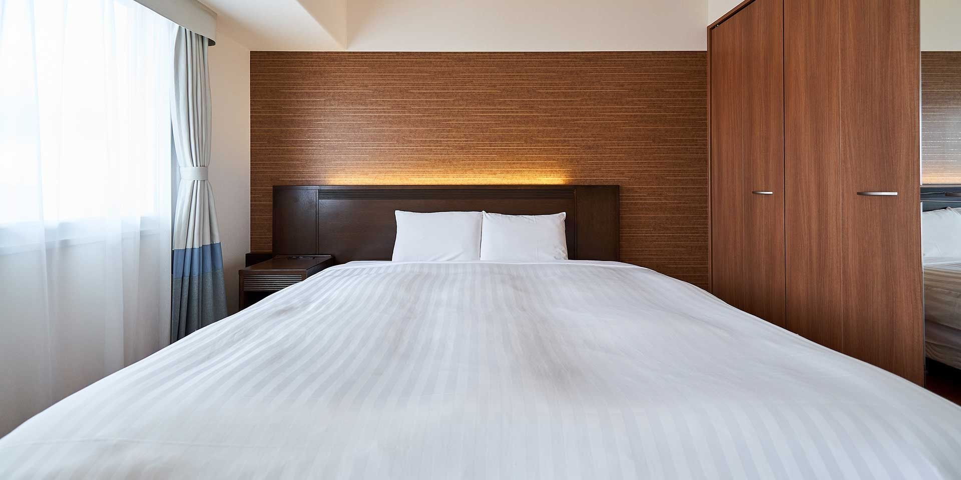 Una habitación de hotel con una cama grande, cabecera de madera y un armario.