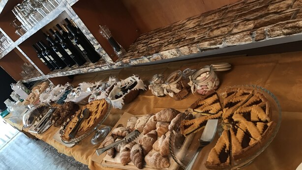A buffet table with various baked goods, including pies and pastries, and a selection of bottled beverages. - Hotel Nova Dhely (Rimini)