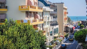 A multi-story hotel with balconies, a street view, and a clear view of the sea. - Hotel Nova Dhely (Rimini)