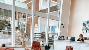 A lobby with two leather armchairs, a glass coffee table, and a reception desk. - Hotell Ronja (Vimmerby)